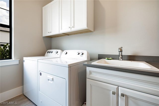 19720 Panther Island Blvd, Estero, FL 33928 - washroom featuring a sink, cabinet space, light wood-style flooring, and washing machine and clothes dryer
