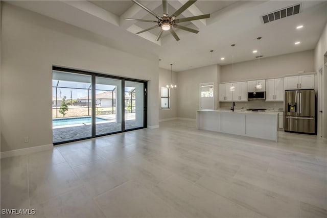 10 NW 13th Pl, Cape Coral, FL 33993 - unfurnished living room with visible vents, baseboards, ceiling fan with notable chandelier, and a high ceiling