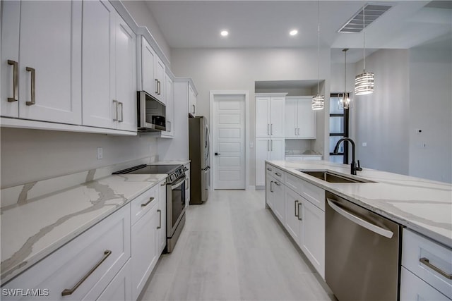 10 NW 13th Pl, Cape Coral, FL 33993 - kitchen featuring visible vents, hanging light fixtures, a sink, white cabinets, and stainless steel appliances