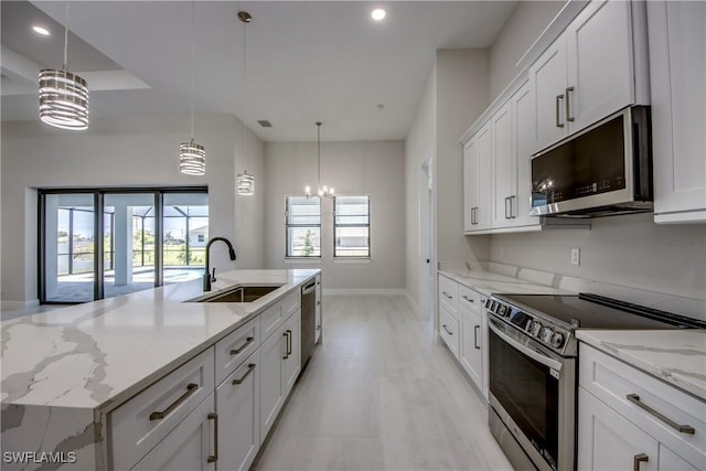 10 NW 13th Pl, Cape Coral, FL 33993 - kitchen featuring a notable chandelier, appliances with stainless steel finishes, a sink, white cabinetry, and baseboards