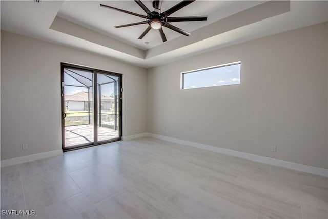 10 NW 13th Pl, Cape Coral, FL 33993 - spare room with baseboards, ceiling fan, light tile patterned floors, and a tray ceiling