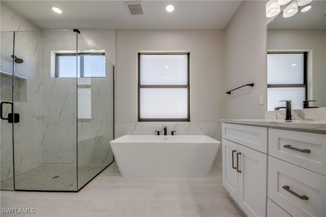 10 NW 13th Pl, Cape Coral, FL 33993 - full bathroom with visible vents, vanity, tile walls, a soaking tub, and a marble finish shower