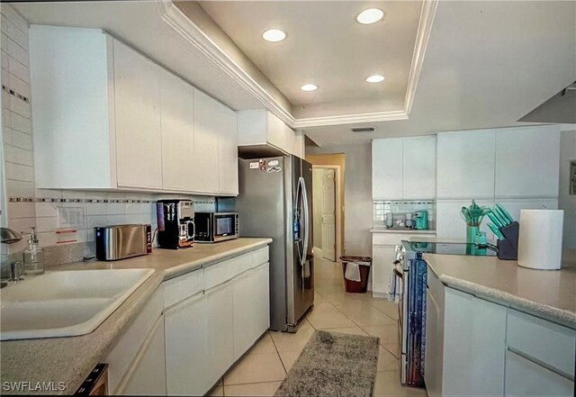 717 SW 49th Ln, Cape Coral, FL 33914 - kitchen featuring stainless steel appliances, a tray ceiling, white cabinetry, light tile patterned flooring, and light countertops
