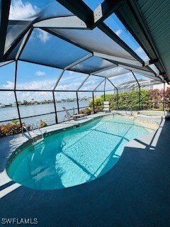 717 SW 49th Ln, Cape Coral, FL 33914 - view of swimming pool featuring a water view, glass enclosure, a pool with connected hot tub, and a patio
