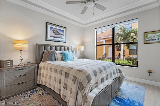 bedroom with a raised ceiling, ornamental molding, baseboards, and a ceiling fan
