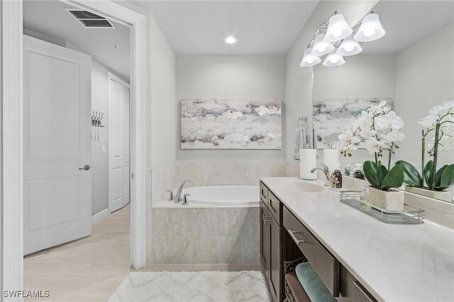 full bathroom featuring visible vents, an inviting chandelier, a garden tub, and vanity