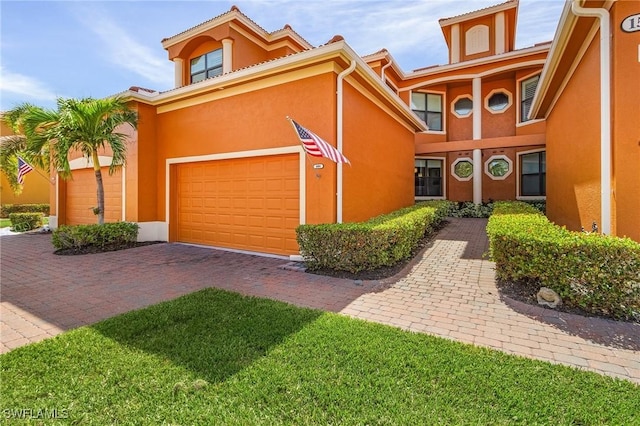 view of front of house with a garage, stucco siding, and decorative driveway