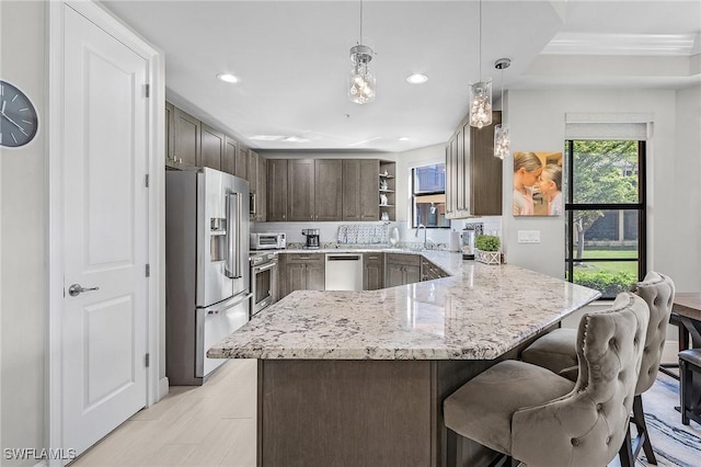kitchen with appliances with stainless steel finishes, open shelves, light stone countertops, dark brown cabinets, and a peninsula