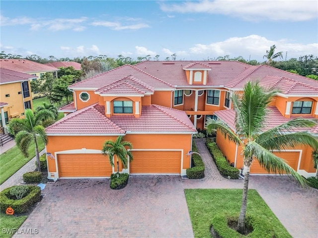 mediterranean / spanish house with a tiled roof, a garage, driveway, and stucco siding
