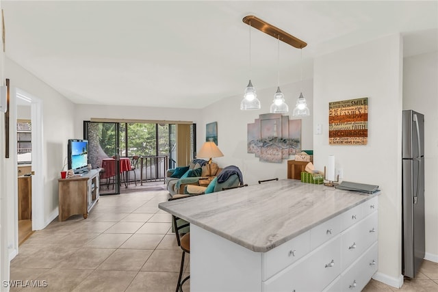 kitchen featuring freestanding refrigerator, light tile patterned flooring, white cabinets, and light stone countertops