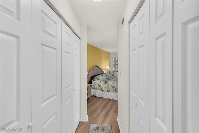 corridor with light wood-type flooring and visible vents