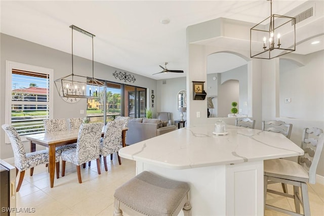 kitchen featuring arched walkways, light stone countertops, visible vents, and a wealth of natural light