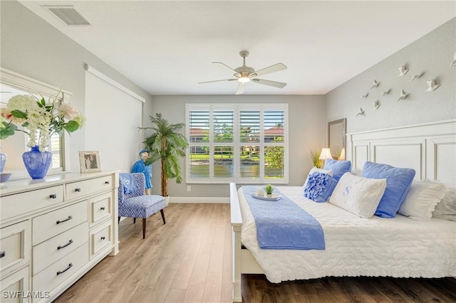 bedroom with baseboards, ceiling fan, visible vents, and light wood-style flooring