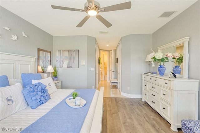 bedroom with a ceiling fan, visible vents, and light wood finished floors