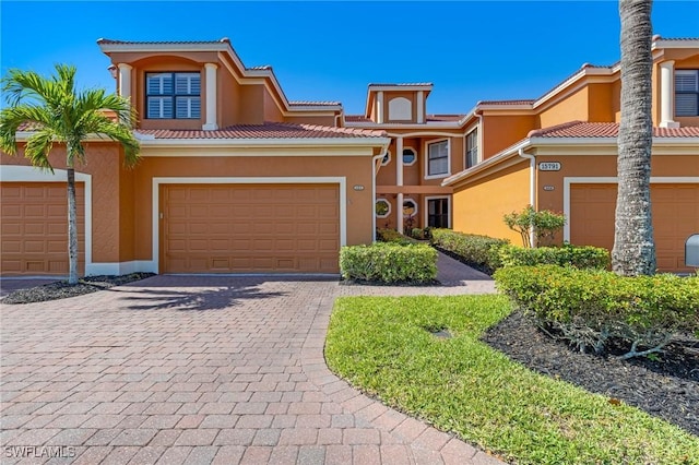 view of front of property with a garage, stucco siding, decorative driveway, and a tiled roof