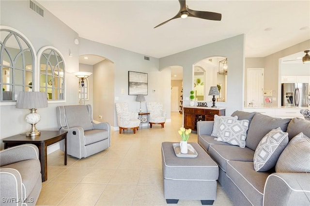 living room with light tile patterned floors, arched walkways, a ceiling fan, and visible vents