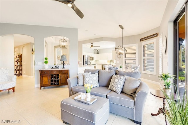 living room with light tile patterned floors, arched walkways, and ceiling fan