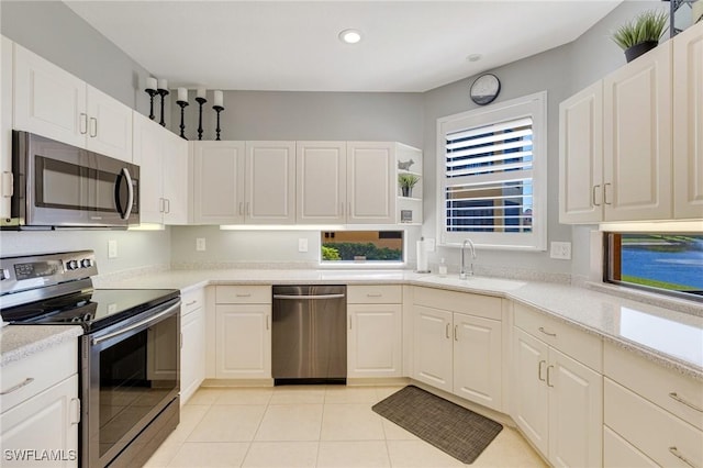 kitchen with light countertops, white cabinets, a sink, appliances with stainless steel finishes, and light tile patterned floors