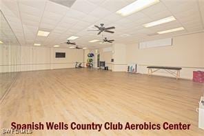 workout room with wood finished floors, a paneled ceiling, and a ceiling fan