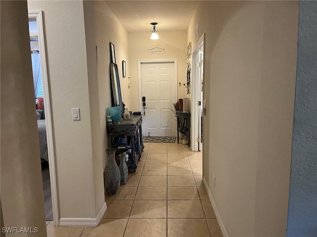 hall featuring light tile patterned floors and baseboards