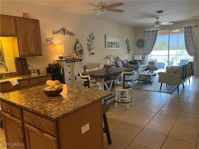 kitchen with ceiling fan, light tile patterned floors, open floor plan, and a kitchen breakfast bar