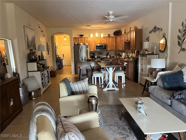 living room featuring ceiling fan, tile patterned flooring, and arched walkways
