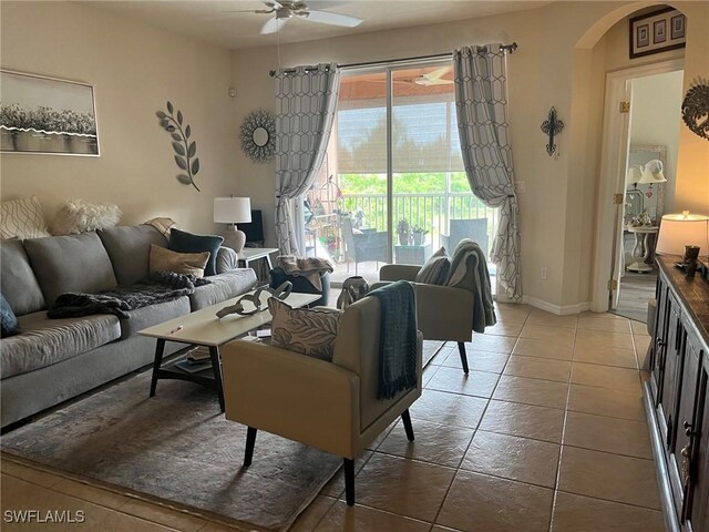 tiled living area with arched walkways, ceiling fan, and baseboards