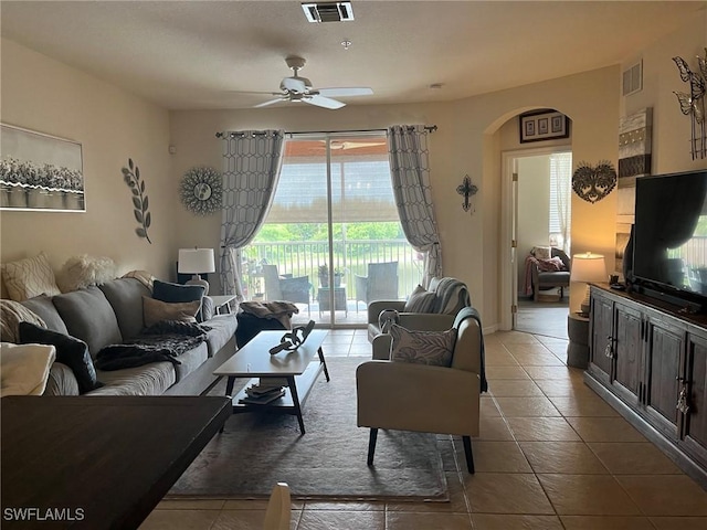 living room featuring ceiling fan, tile patterned floors, and arched walkways
