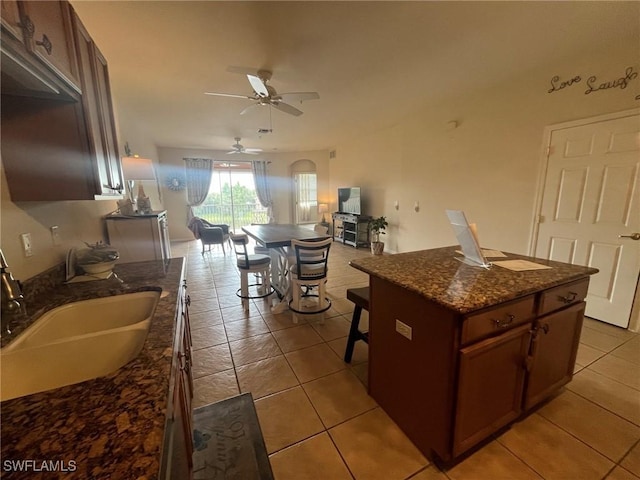 9631 Spanish Moss Way Unit 3931, Bonita Springs, FL 34135 - kitchen with open floor plan, a ceiling fan, light tile patterned flooring, dark stone countertops, and a center island
