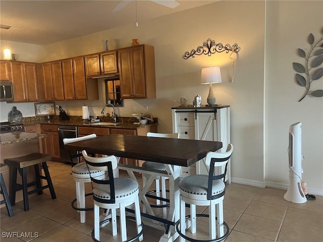 9631 Spanish Moss Way Unit 3931, Bonita Springs, FL 34135 - kitchen featuring dark countertops, appliances with stainless steel finishes, light tile patterned floors, brown cabinets, and ceiling fan