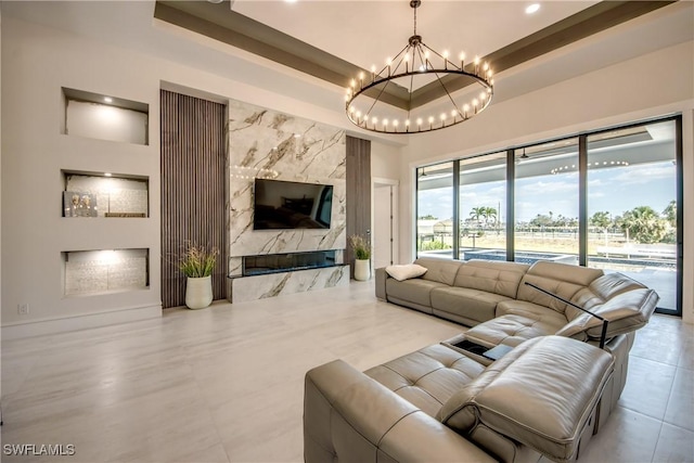 living area featuring an inviting chandelier, a raised ceiling, tile patterned floors, and a fireplace
