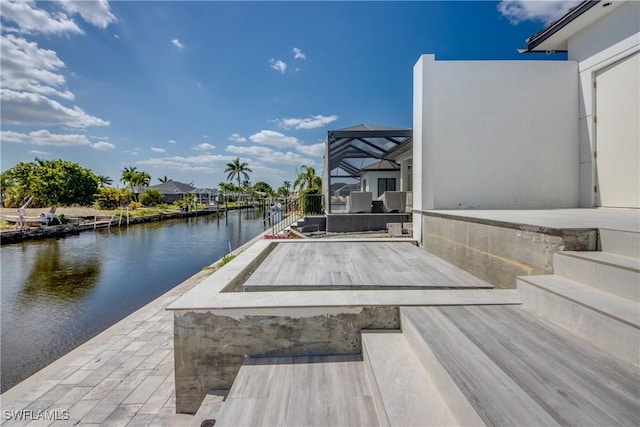 view of dock with glass enclosure and a water view