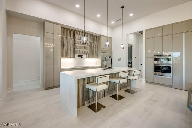 kitchen featuring light countertops, stainless steel appliances, modern cabinets, and a kitchen bar
