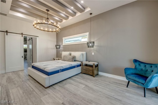bedroom with baseboards, a chandelier, a barn door, and wood finished floors