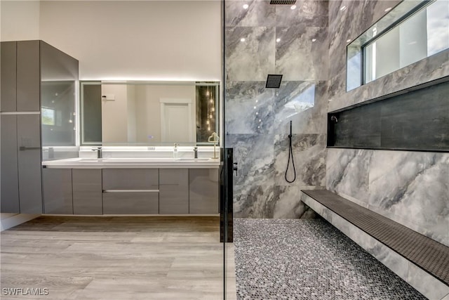 bathroom with a sink, double vanity, a walk in shower, and wood finished floors