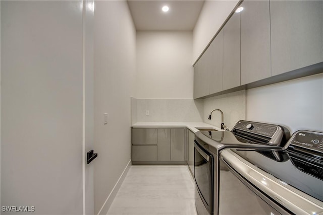 laundry room featuring recessed lighting, light wood-style flooring, separate washer and dryer, a sink, and cabinet space