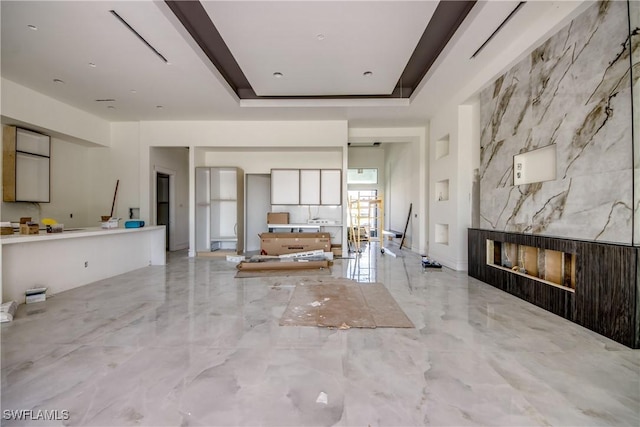 living room with a raised ceiling, marble finish floor, and a fireplace