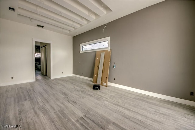 spare room with baseboards, light wood-style flooring, and visible vents