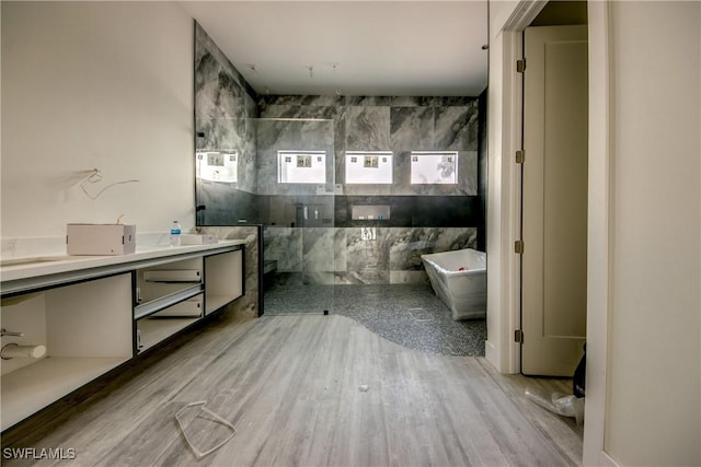 bathroom featuring a freestanding bath, vanity, walk in shower, and wood finished floors