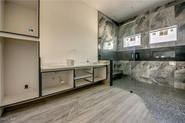 bathroom featuring a marble finish shower, vanity, and wood finished floors