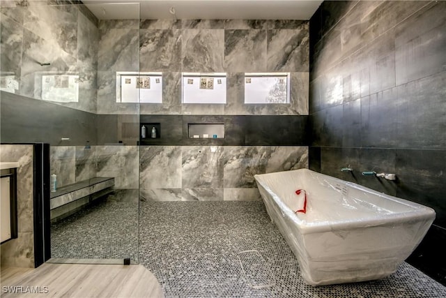 bathroom featuring tile walls and a soaking tub
