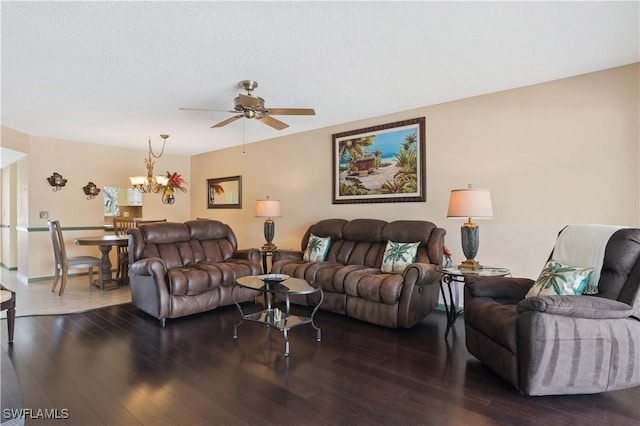 living room featuring a textured ceiling, dark wood-style flooring, and ceiling fan with notable chandelier
