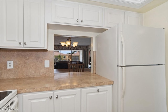 kitchen with white appliances, light countertops, a chandelier, white cabinets, and tasteful backsplash