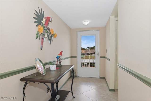 doorway with light tile patterned floors and baseboards
