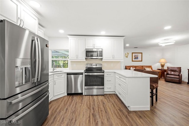 6012 Perthshire Ln, Fort Myers, FL 33908 - kitchen featuring stainless steel appliances, a peninsula, a sink, wood finished floors, and recessed lighting