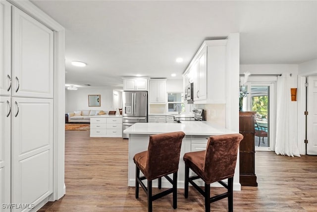 6012 Perthshire Ln, Fort Myers, FL 33908 - kitchen featuring stainless steel appliances, wood finished floors, white cabinets, light countertops, and a peninsula