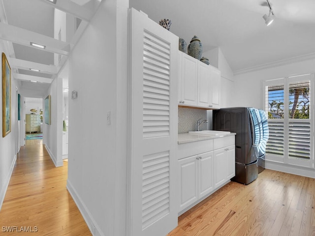 8315 Main St, Bokeelia, FL 33922 - laundry area with baseboards, light wood-style flooring, rail lighting, a sink, and cabinet space