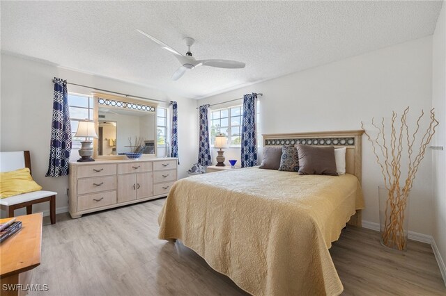 15400 River Vista Dr Unit 304, North Fort Myers, FL 33917 - bedroom featuring baseboards, a textured ceiling, light wood-style flooring, and a ceiling fan