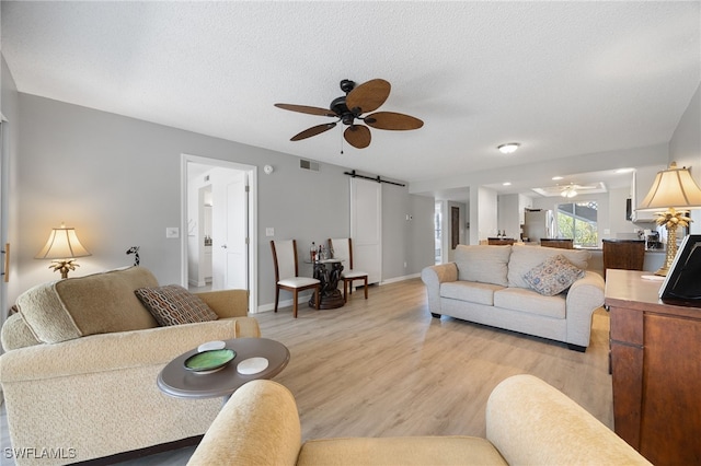 15400 River Vista Dr Unit 304, North Fort Myers, FL 33917 - living room featuring visible vents, a barn door, light wood finished floors, and ceiling fan