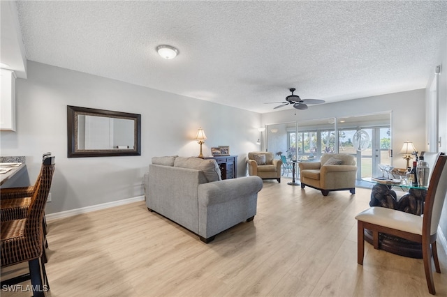 15400 River Vista Dr Unit 304, North Fort Myers, FL 33917 - living area featuring light wood-style floors, baseboards, a ceiling fan, and a textured ceiling